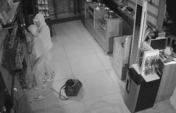 Imagem preta e branca de dois homens dentro de joalheria - Metrópoles