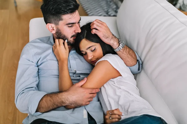 Foto colorida de casal deitado em sofá
