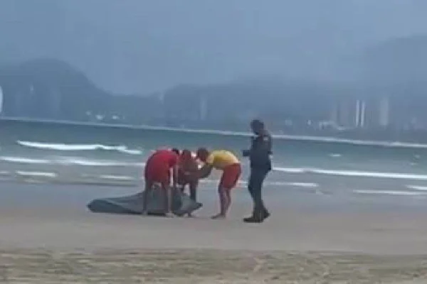 Bombeiros e policial militar colocam corpo encontrado no Guarujá, SP, na areia- Metrópoles