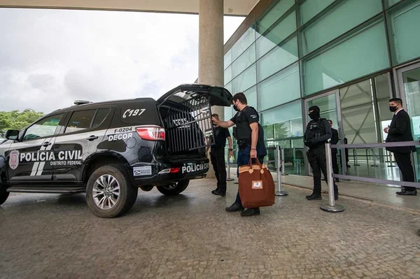 Viatura da PCDF com homens de preto carregando malas