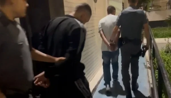 Imagem de dois policiais conduzindo dois detentos para delegacia - Metrópoles