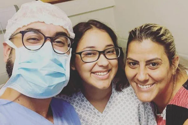 Foto colorida: três pessoas olhando para a câmera sorrindo