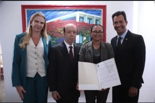 Imagem colorida de pessoas umas ao lado das outras. Uma mulher segura a escritura de uma casa títulos de propriedade - Metrópoles