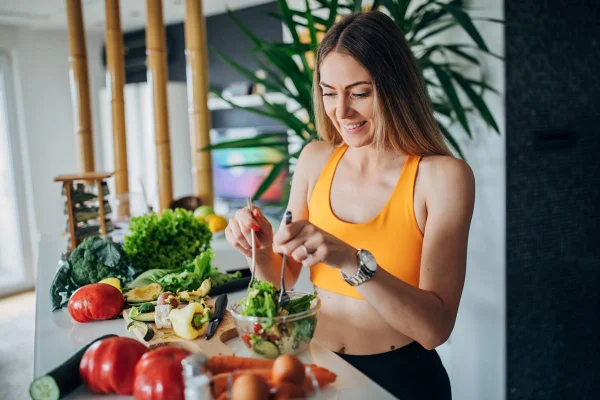 Foto colorida de mulher preparando salada - Metrópoles