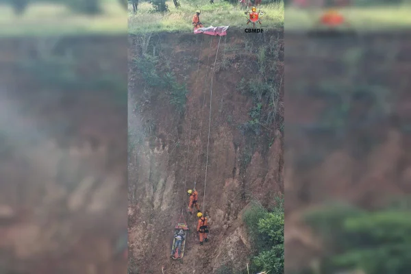 Foto colorida de bombeiros resgatando homem que caiu em ribanceira