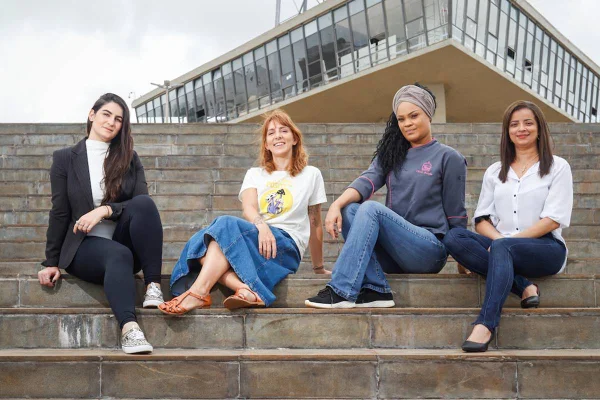 quatro mulheres sentadas na escada com torre de tv ao fundo