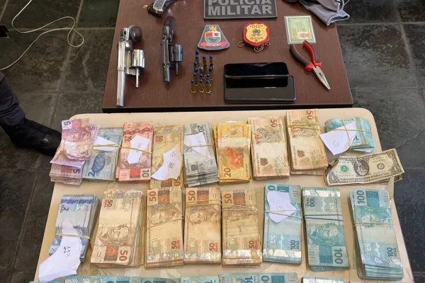 Foto colorida de dinheiro roubado de comerciante e armas usadas por ladrões, no interior de São Paulo.