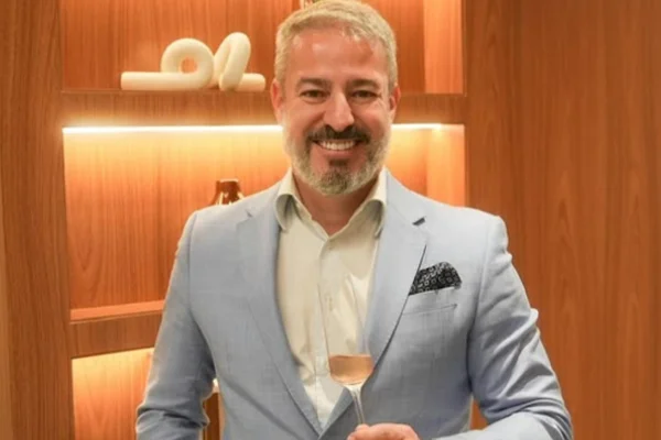 Cirurgião plástico Renato Tatagiba sorri em foto com espumante. - Metrópoles