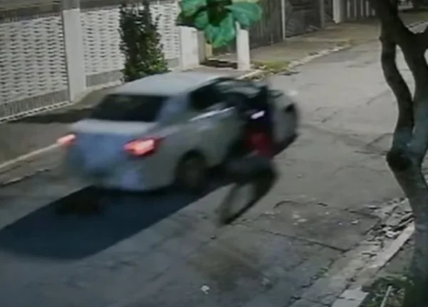 Imagem mostra carro branco arrastando uma mulher durante tentativa de assalto - Metrópoles