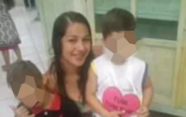 Em foto colorida mulher de cabelos negros e solto sorri, agachada, tendo em cada um de seus lados um menino - Metrópoles