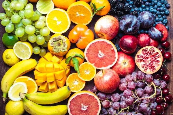 Um espectro colorido de frutas: laranjas, limões, limas, tangerinas, uvas, ameixas, toranjas, romãs, caquis, bananas, cerejas, maçãs, mangas, amoras e mirtilos.