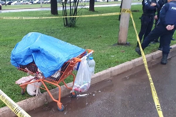 Fotografia colorida mostra cena de crime isolada, com carrinho de compras e faca no chão