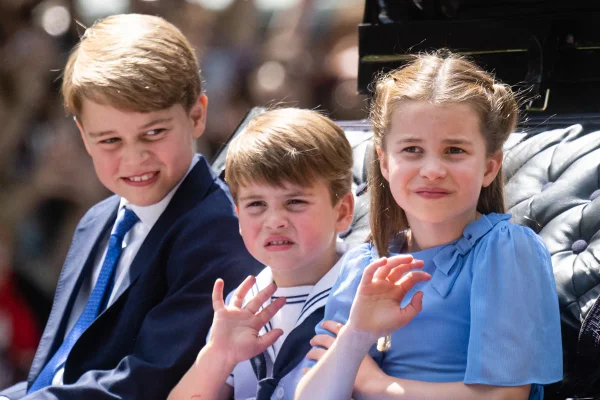 Foto colorida de três crianças branca e loiras acenando e com cara triste - Metrópoles