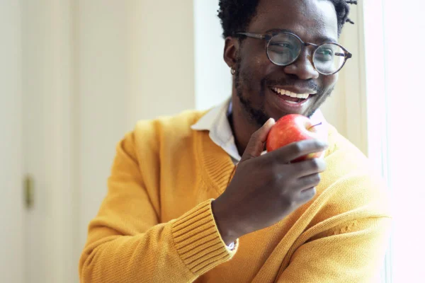 Foto colorida homem negro comendo fruta