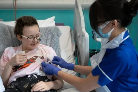 Foto colorida da adolescente Alyssa recebendo tratamento para leucemia