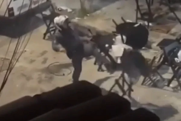 Captura de tela colorida de vídeo que mostra policial da Rocam quebrando mesa em adega da zona leste de São Paulo. - Metrópoles
