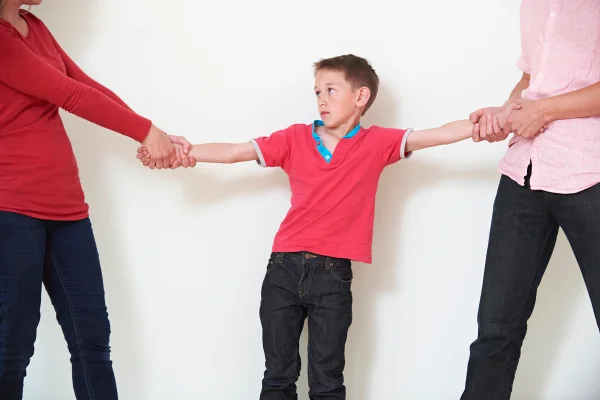 Pais segurando o filho pelo braço para representar a briga pela guarda no divórcio