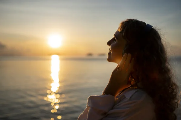 Foto de mulher sorrindo em frente ao pôr do sol - Metrópoles