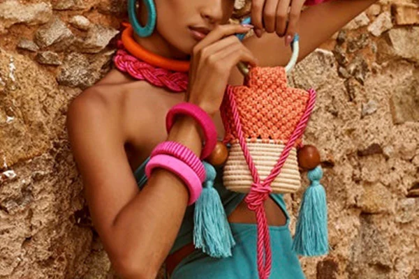 Modelo usa acessórios coloridos e mostra detalhes de bolsa colorida feita de crochê - Metrópoles