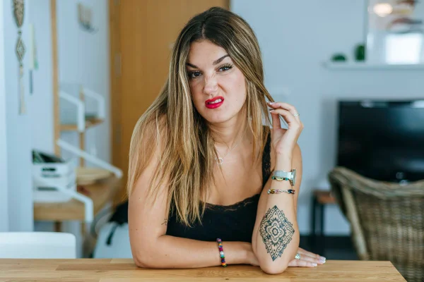 Foto colorida de mulher com cara feia, usando batom rosa e vestindo blusa preta - Metrópoles.