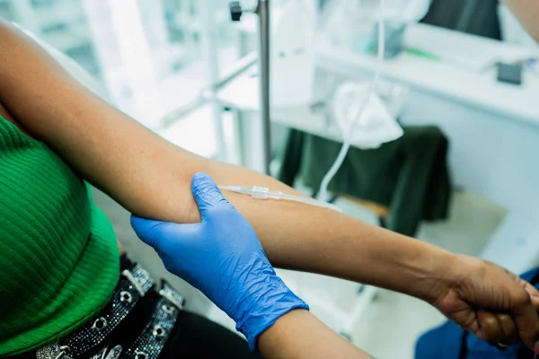 Close-up de um médico aplicando soro intravenoso em um paciente no consultório médico. Metrópoles
