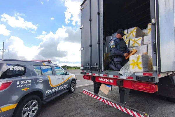 Imagem colorida mostra policial com carga de maconha encontrada eem caixas de óleo vegetal no interior de São Paulo - Metrópoles