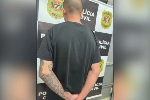 Imagem colorida mostra homem de camiseta preta de costas com as mãos para trás; rapaz foi preso pela Polícia Civil por balear um homem em uma festa - Metrópoles