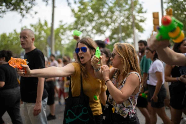 imagem colorida. Manisfestantes atirando com pistola de água em turistas em Barcelona