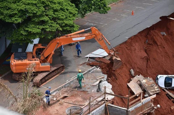 Escavadeira prepara a retirada de carros da cratera na Asa Sul