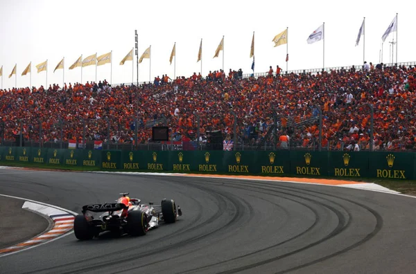 imagem colorida de pista de corria e carro em fazendo curva para a esquerda e arquibancada lotada na direita no GP da Holanda- Metrópoles