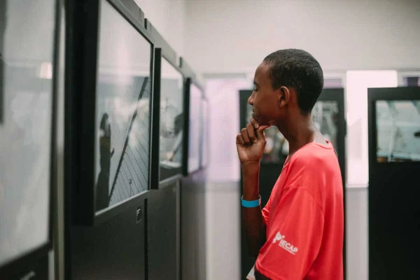 Foto colorida de menino usando blusa vermelha e admirando exposição - Metrópoles