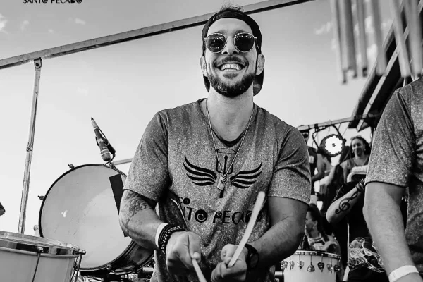 Vinícius Jubinha sorrindo e de óculos, tocando em instrumento - Metrópoles