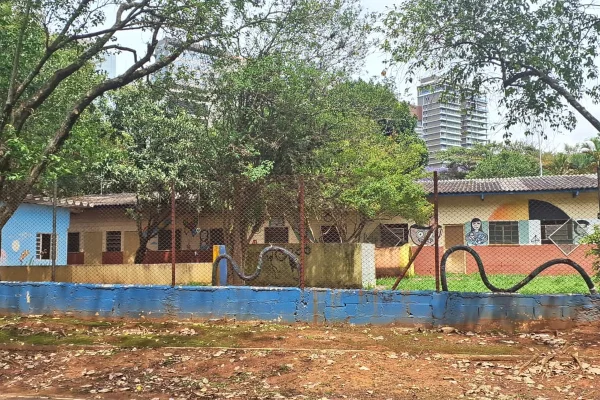 Imagem de uma creche abandonada pela prefeitura de São Paulo, mostra um prédio colorido, de um único andar térreo, com paredes coloridas, atrás de uma grade.