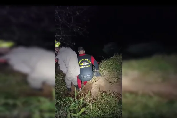 Imagem colorida de dois bombeiros em uma cachoeira, com pouca iluminação