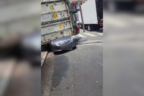 imagem colorida de caminhão que tombou em cima de carro. Metrópoles