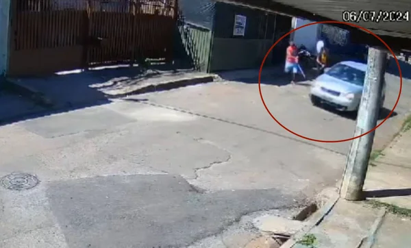 Imagem colorida de um carro trafegando ao lado de duas pessoas - Metrópoles