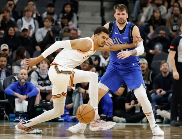 Victor Wembanyama #1 do San Antonio Spurs tenta salvar a bola após Luka Doncic #77 do Dallas Mavericks afastar dele em 19 de março 2024