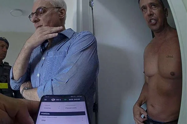 Policiais e homem sem camisa conversam denro de partamento - Metrópoles