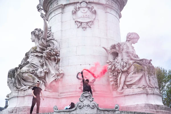 homem segura iluminador vermelho em frente a monumento em paris