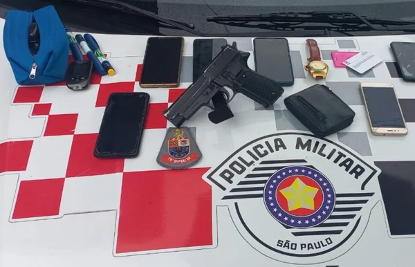 Imagem mostra celulares, relógios e arma falsa sobre símbolo da PM - Metrópoles