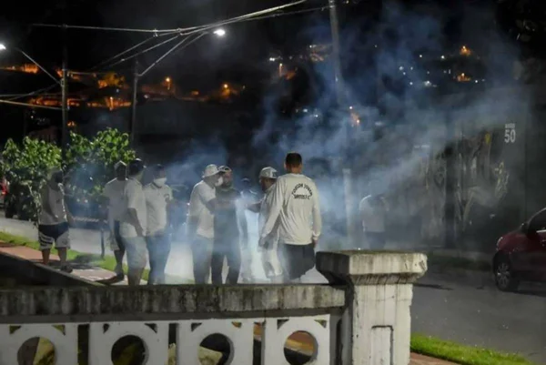 Torcedores de mascara na rua em meio a fumaça