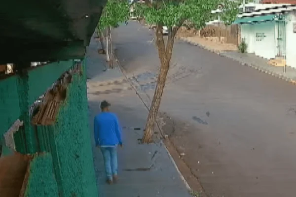 Imagem colorida de um homem de moletom azul e boné andando em uma calçada - Metrópoles