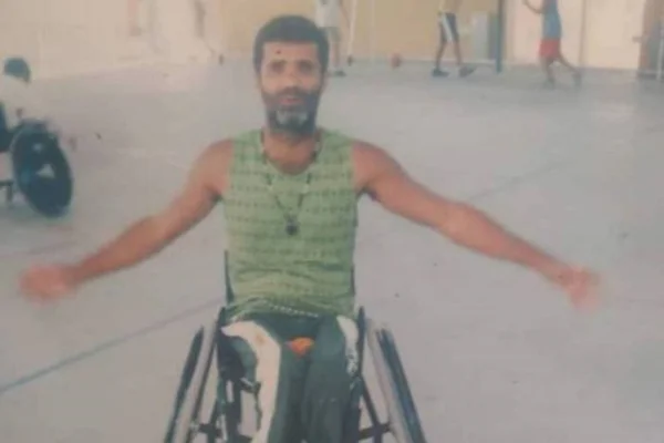 Homem em cadeira de rodas, vítima de bala perdida posa para foto abrindo os braços