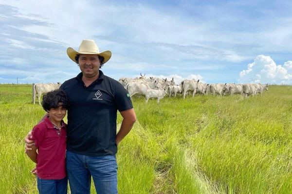 foto de homem com criança e ao fundo pasto com bois