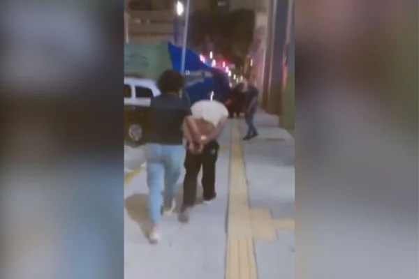 Imagens coloridas mostram homem de costas, algemado com as mãos para trás, sendo conduzido até uma viatura por uma policial