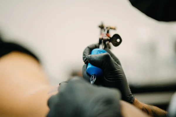 Foto colorida de uma mulher tatuando - Metrópoles
