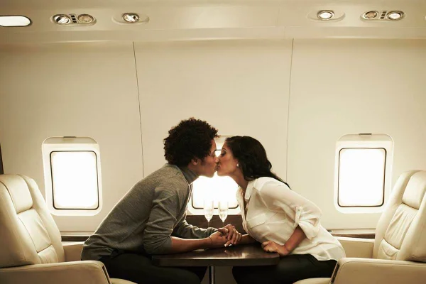Foto colorida de casal se beijando no avião - Metrópoles