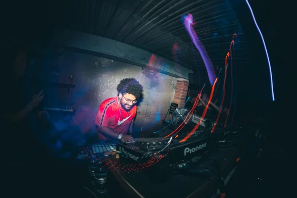 DJ negro, com cabelo black, se apresentando. Usa camisa vermelha. - Metrópoles