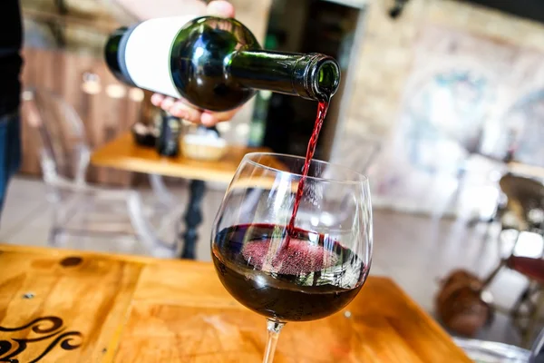 Um vinho tinto é colocado da garrafa para a taça
