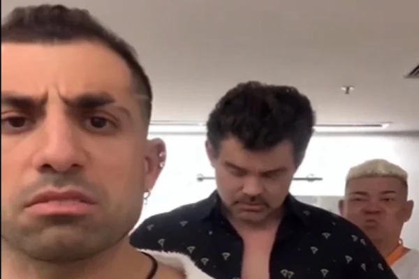 Foto colorida de Kaysar e Carmo Dalla Vecchia. Kaysar está em primeiro plano, usa uma camisa branca aberta. Carmo está mais atrás, com uma camisa preta aberta - Metrópoles